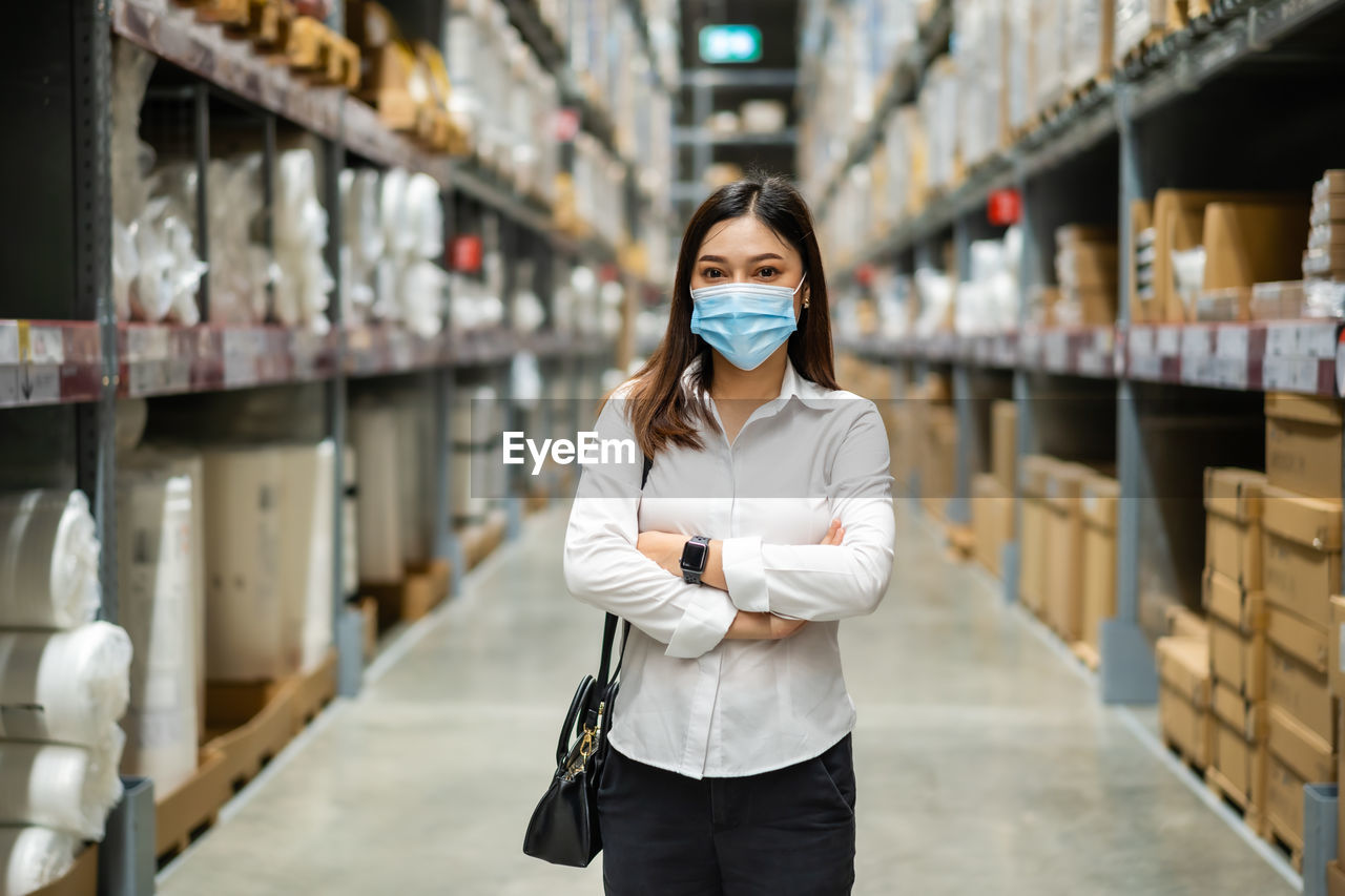 Portrait of woman wearing mask standing in warehouse