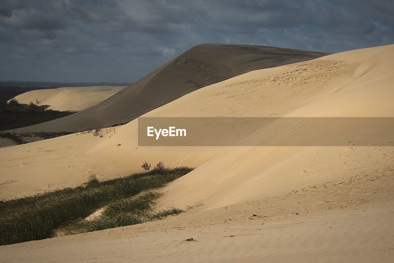 Scenic view of desert against cloudy sky