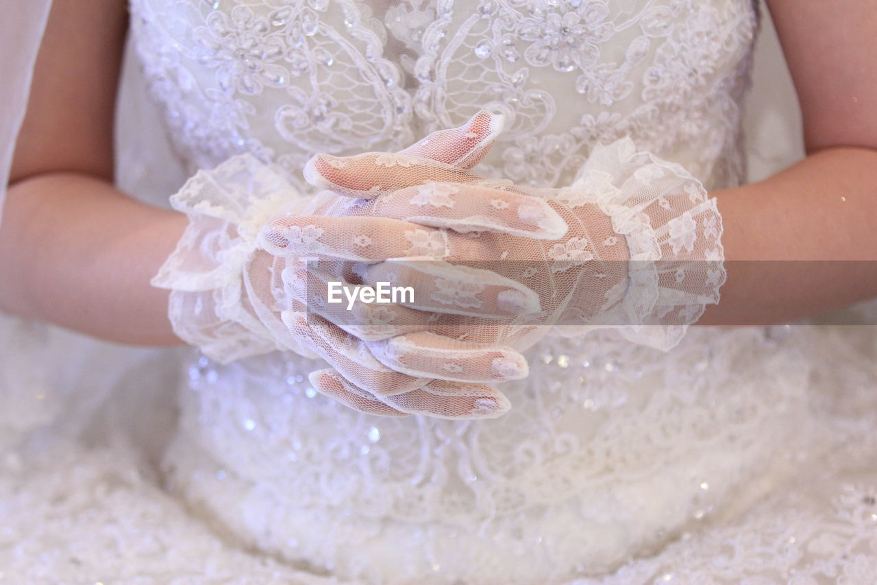 Midsection of bride with fingers intertwined