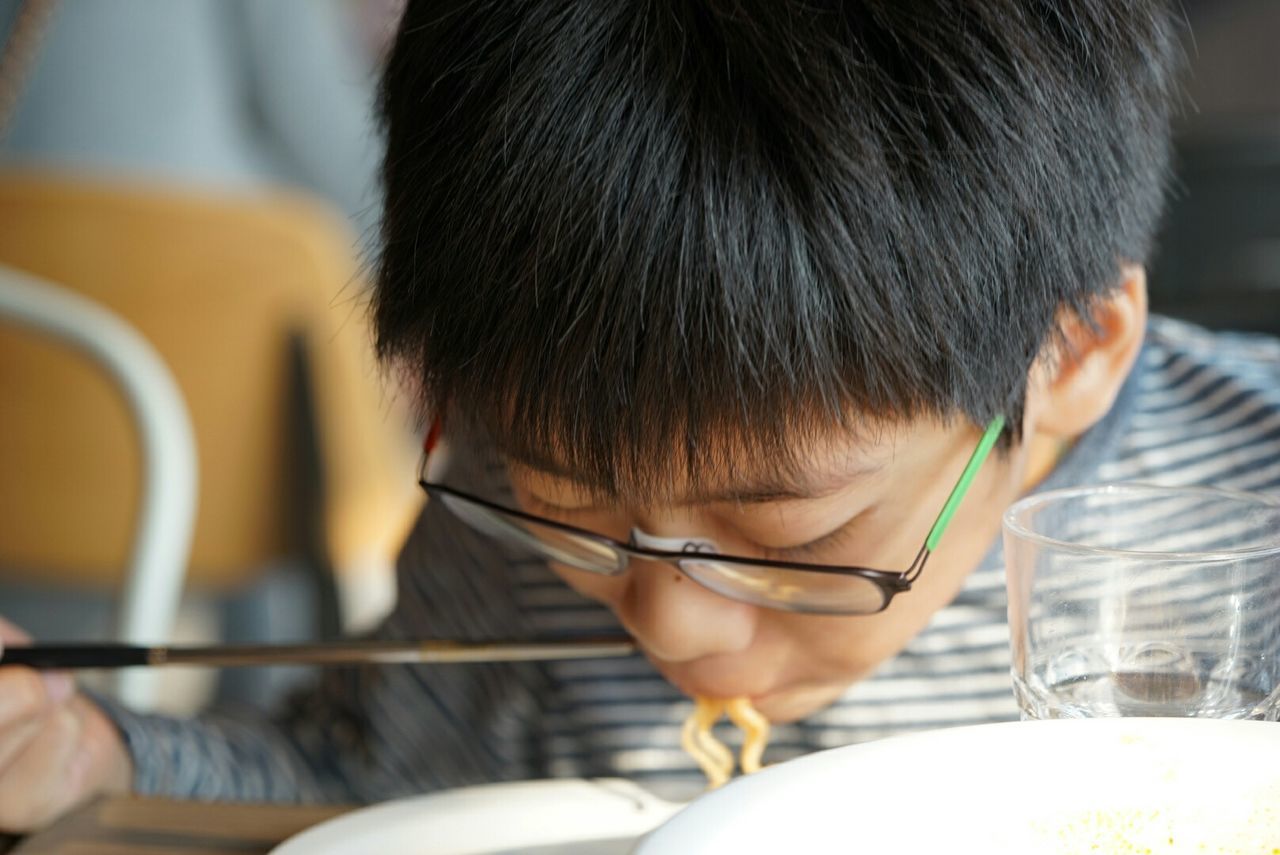 Close-up of boy eating noodles on table