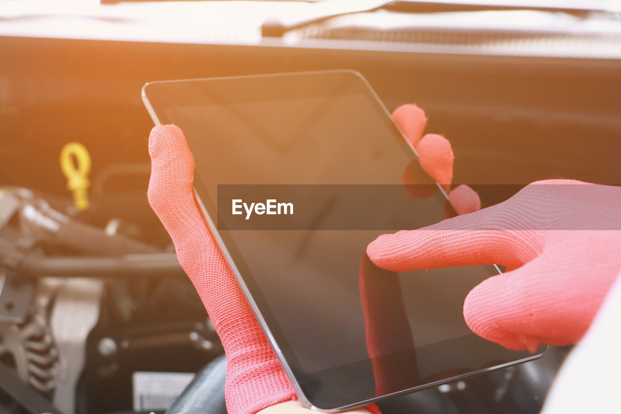 Cropped hands of mechanic using digital tablet