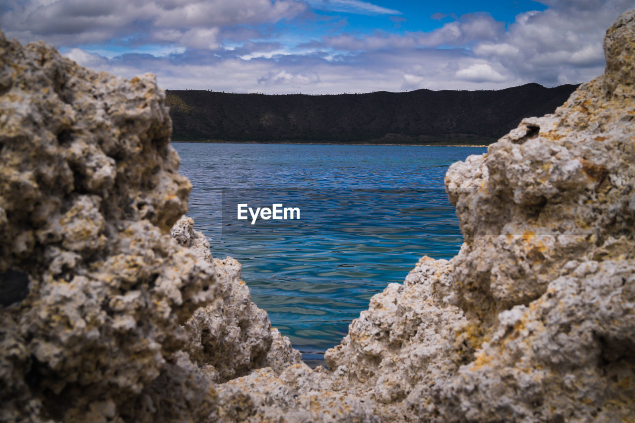 ROCK FORMATIONS ON SHORE AGAINST SKY