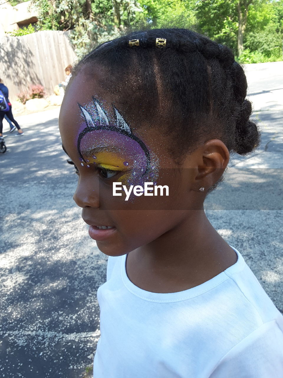 Close-up of thoughtful girl with face paint standing on footpath