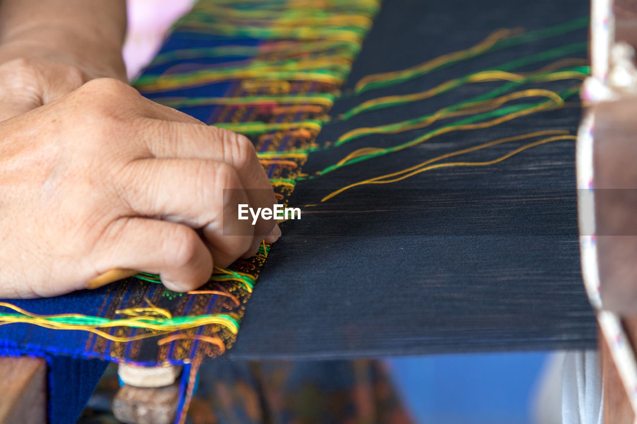 Cropped hand of woman weaving