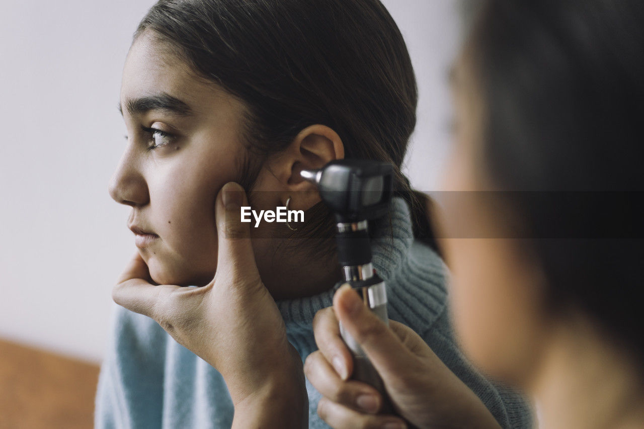 Doctor doing hearing test of female patient through otoscope at hospital