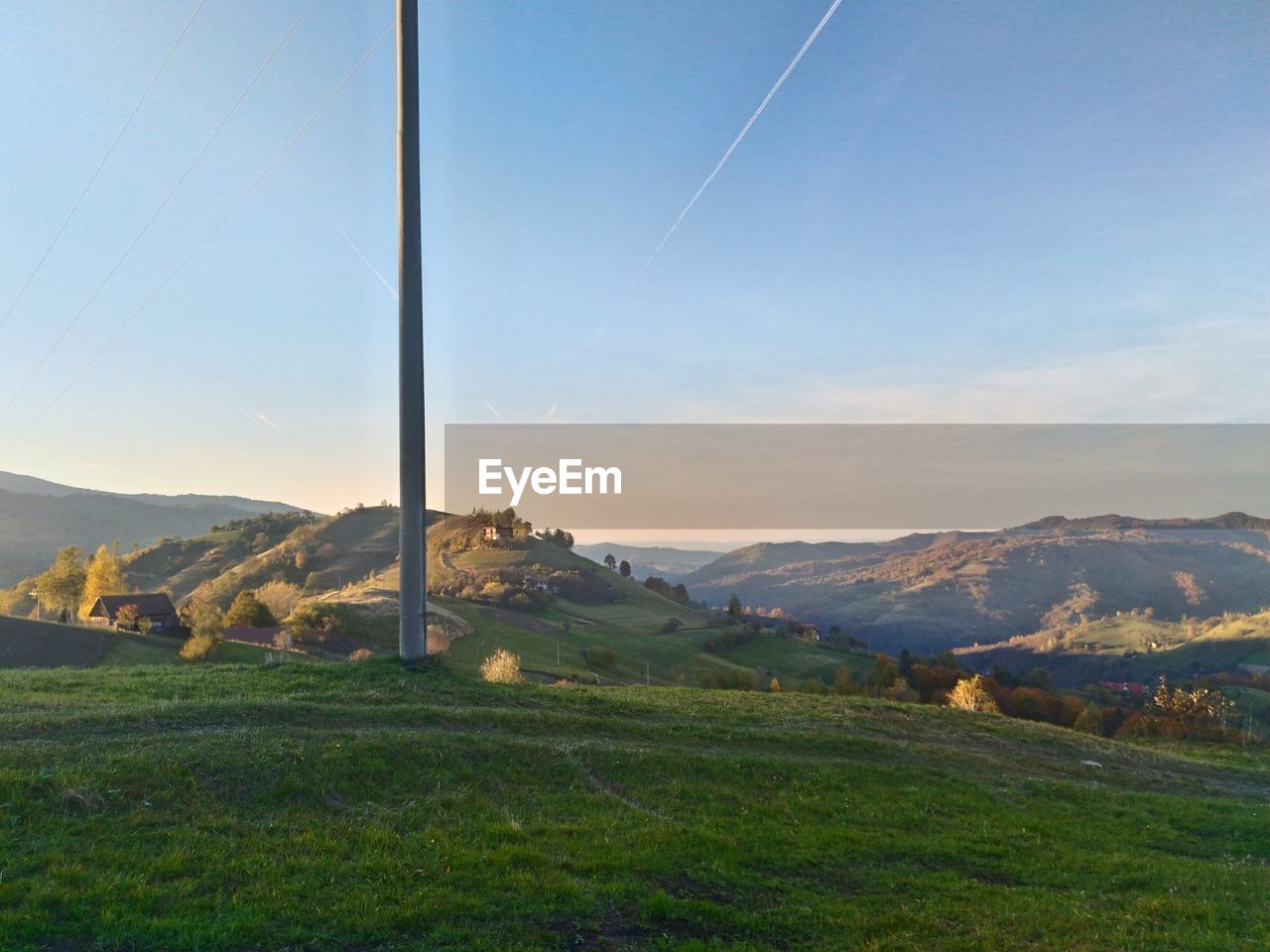 COUNTRYSIDE LANDSCAPE AGAINST BLUE SKY AND MOUNTAINS