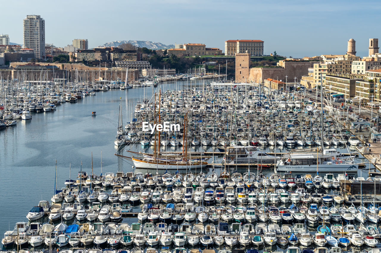 Aerial view of boats moored at harbor against buildings