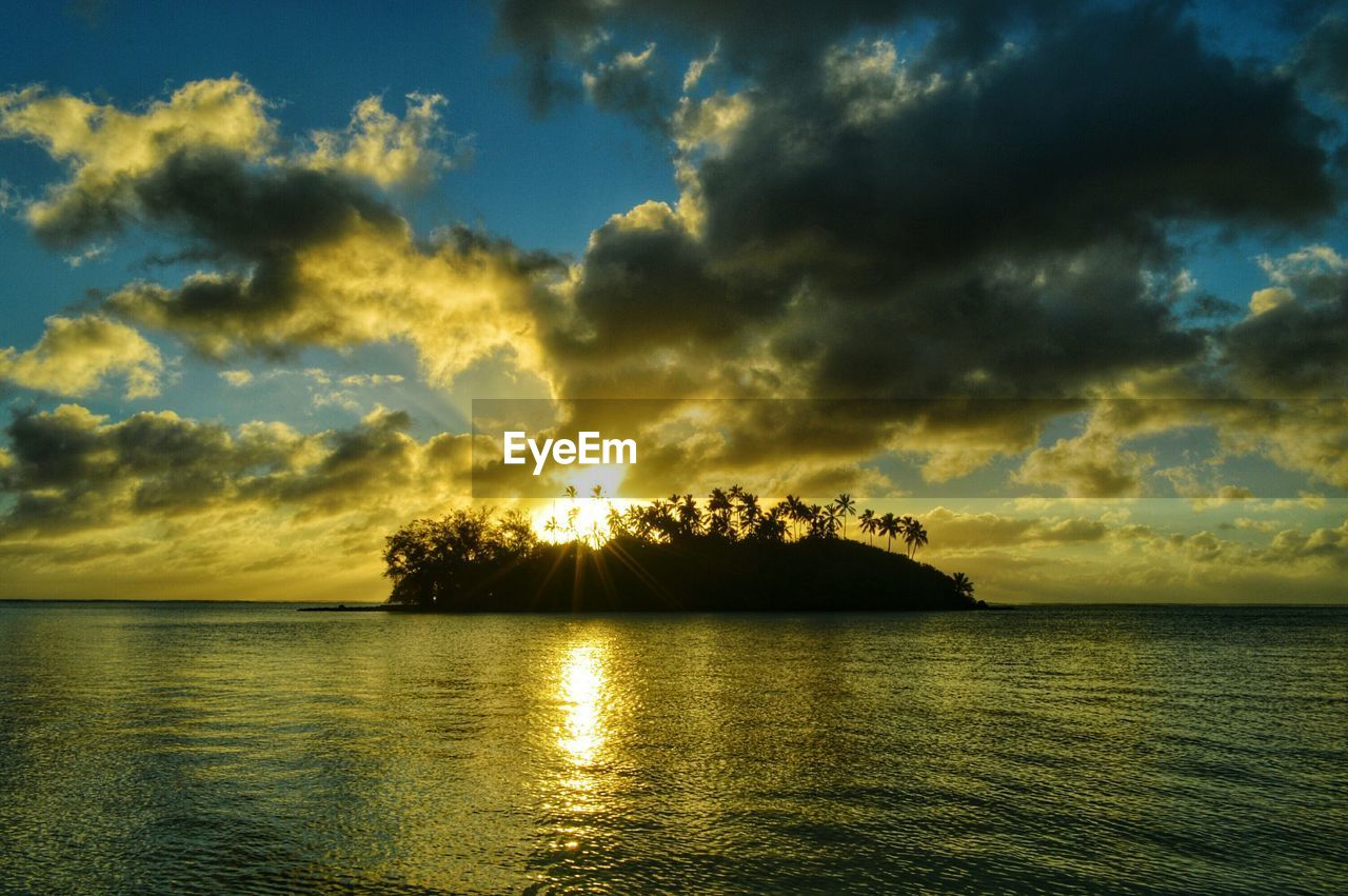 Scenic view of sea against cloudy sky at sunset