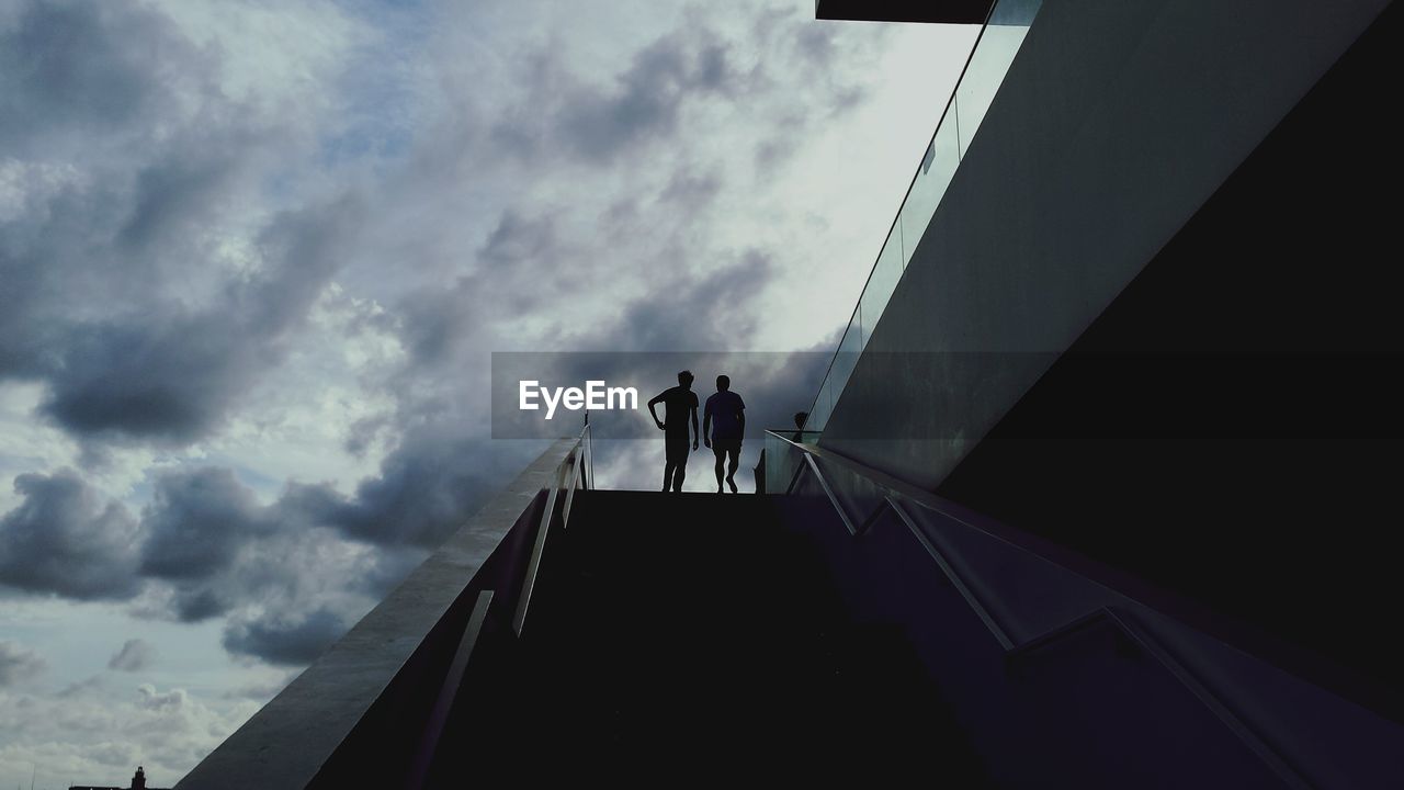 Low angle view of men on staircase against sky