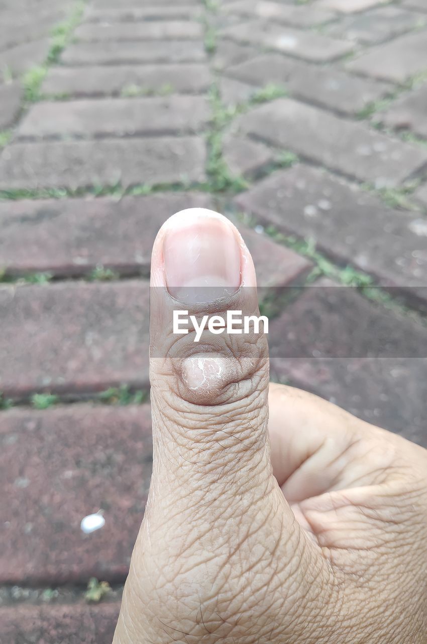 CLOSE-UP OF HUMAN HAND AGAINST BLURRED BACKGROUND