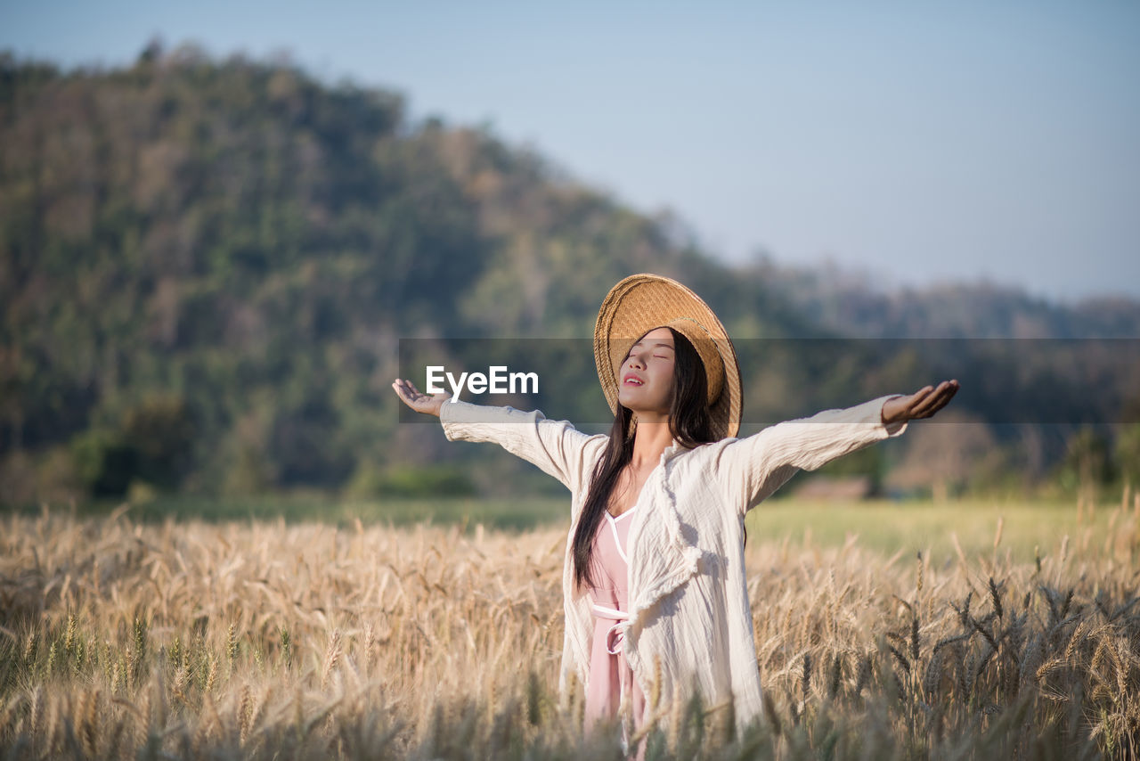 Woman with arms outstretched standing on field