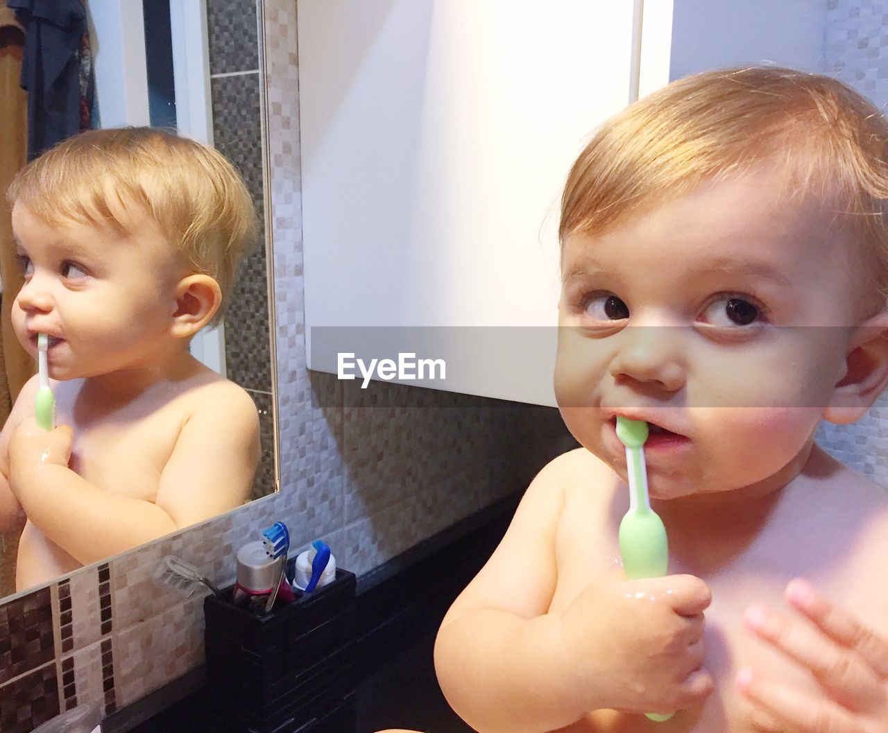 Close-up of cute baby boy brushing teeth in bathroom