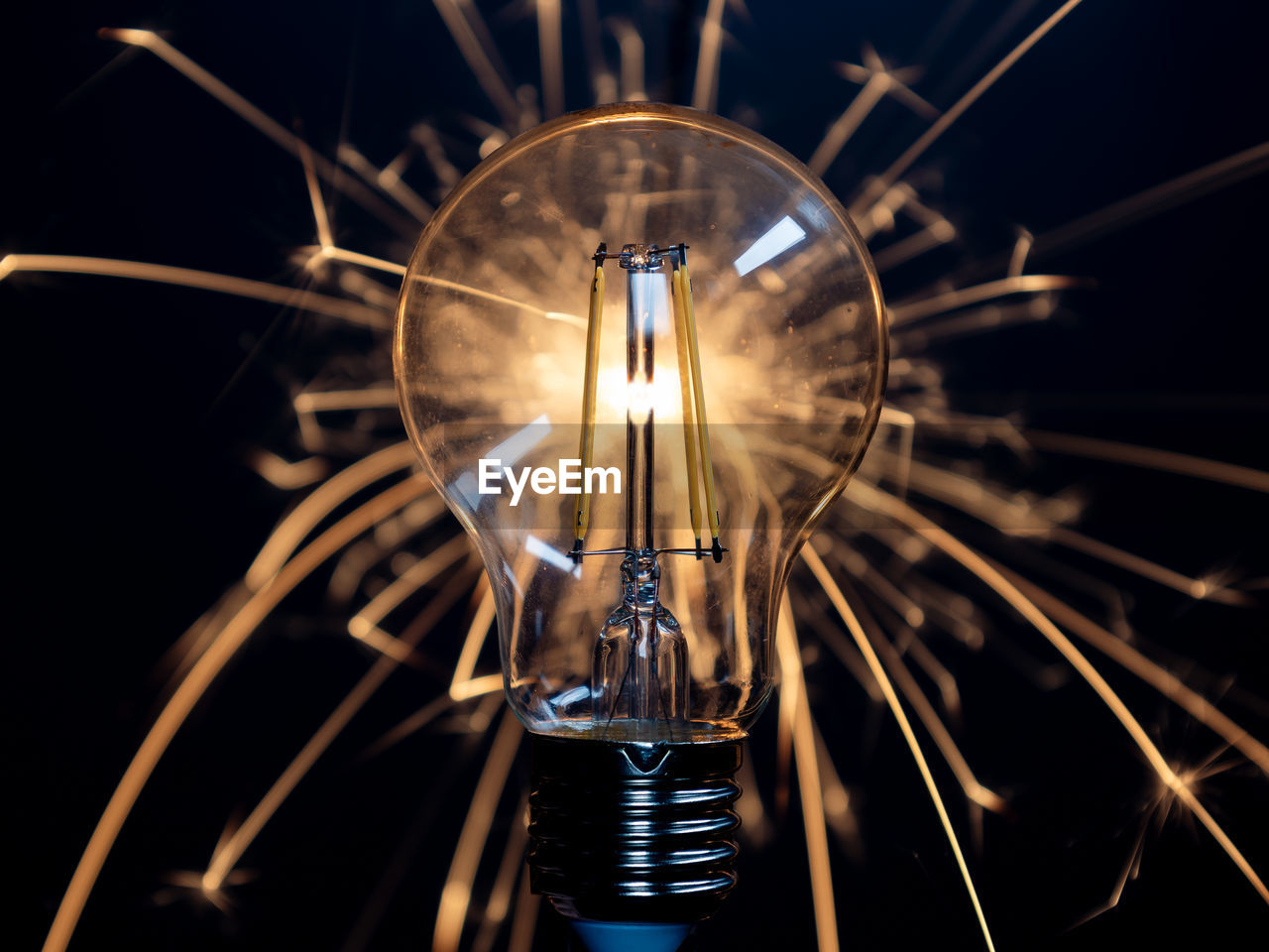 A light bulb with transparent glass in the dark with sparklers behind it