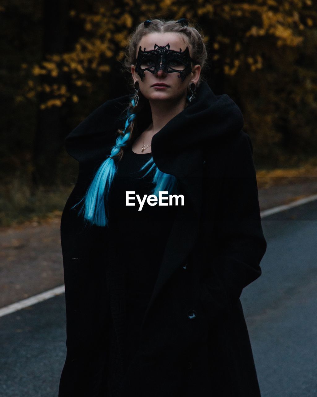 Portrait of young woman wearing mask while standing on road