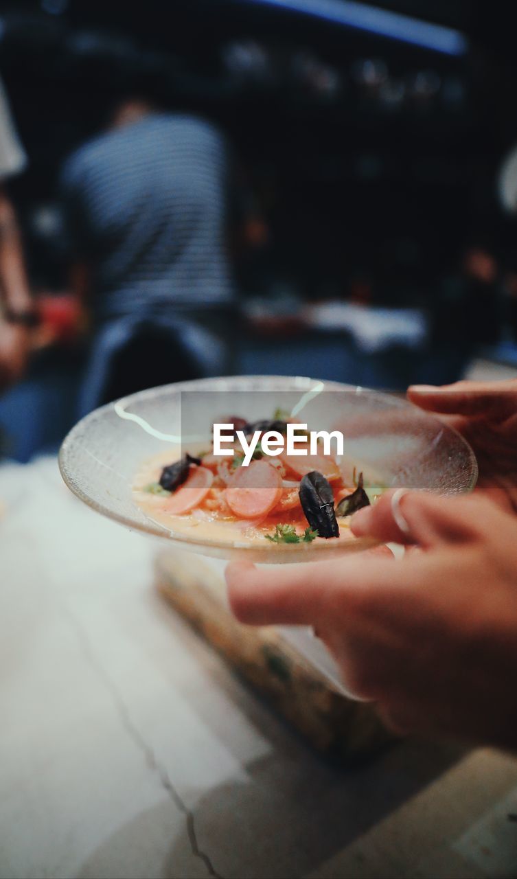 Cropped hands holding food in plate