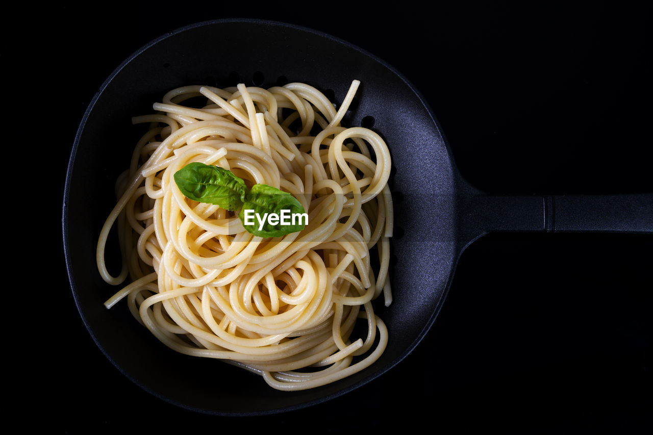 pasta, food, italian food, food and drink, black background, healthy eating, studio shot, spaghetti, indoors, freshness, kitchen utensil, wellbeing, vegetable, no people, cuisine, carbonara, household equipment, meal, high angle view, directly above, close-up, herb, produce, eating utensil, dish, still life