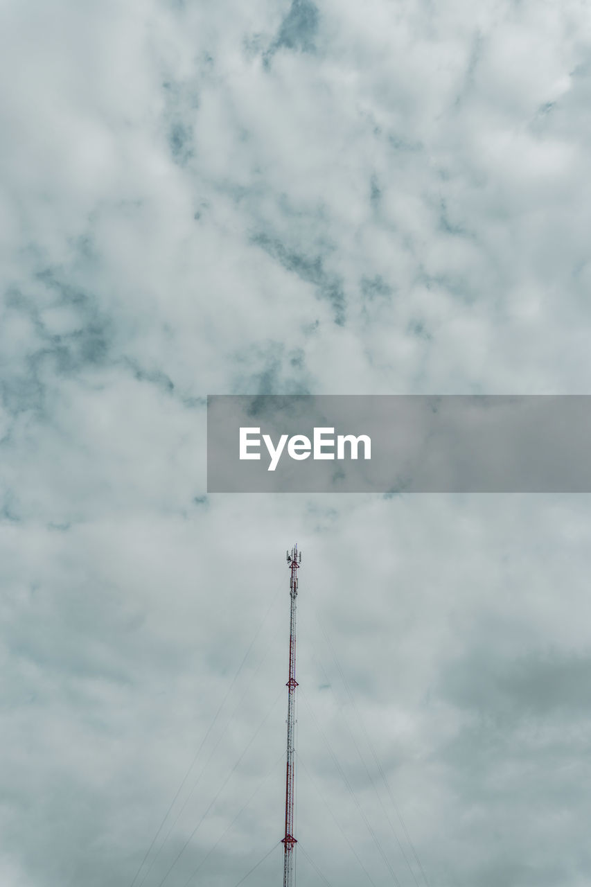 Low angle view of communications tower against cloudy sky