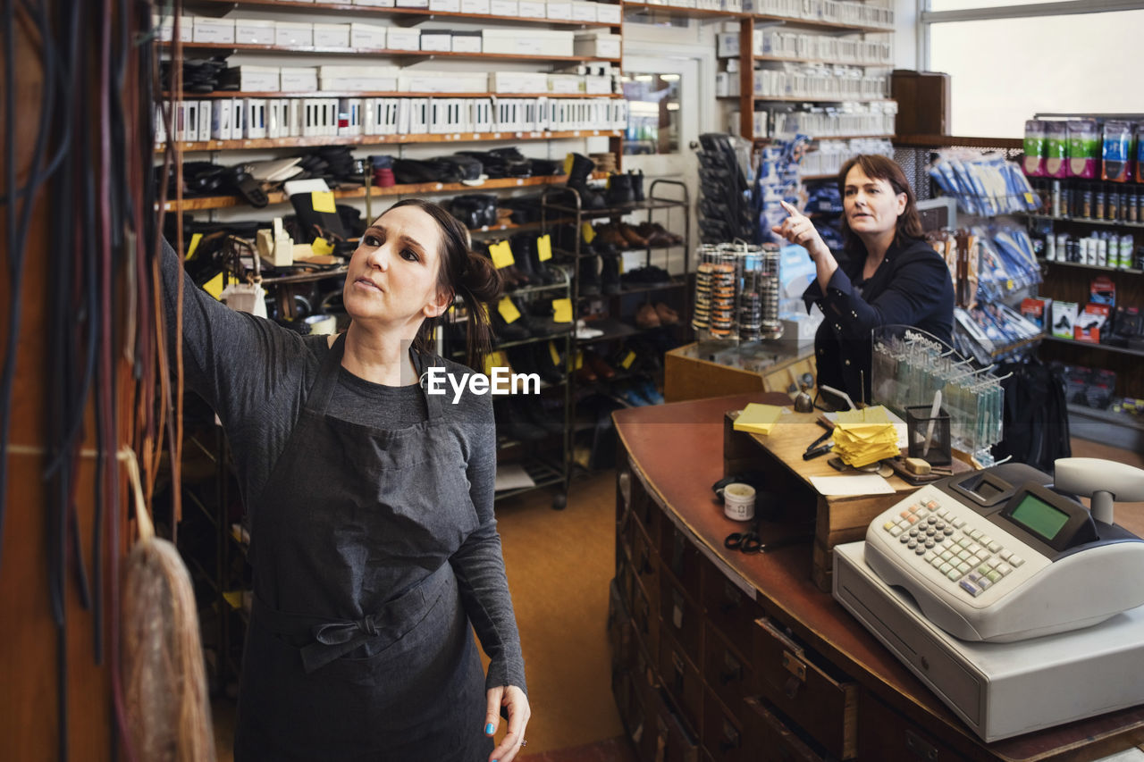 Shoemaker assisting female customer at repair store