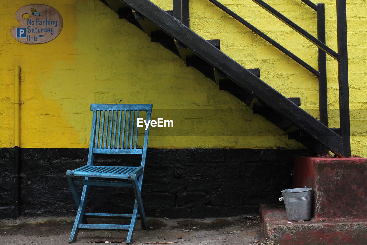 Empty chairs against yellow wall