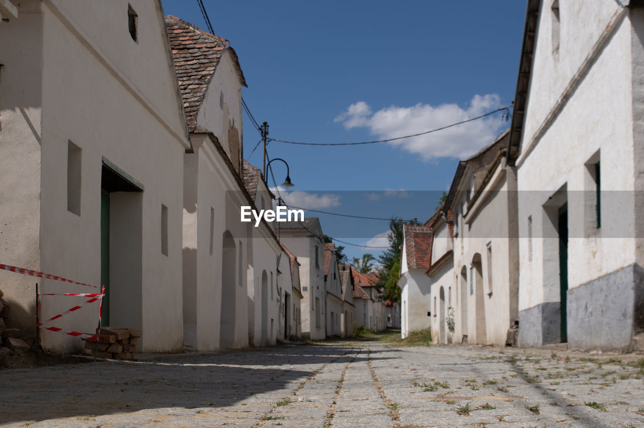 architecture, building exterior, town, neighbourhood, street, built structure, building, road, city, alley, sky, urban area, village, residential district, nature, residential area, no people, infrastructure, house, lane, facade, day, outdoors, cloud, footpath, wall, old