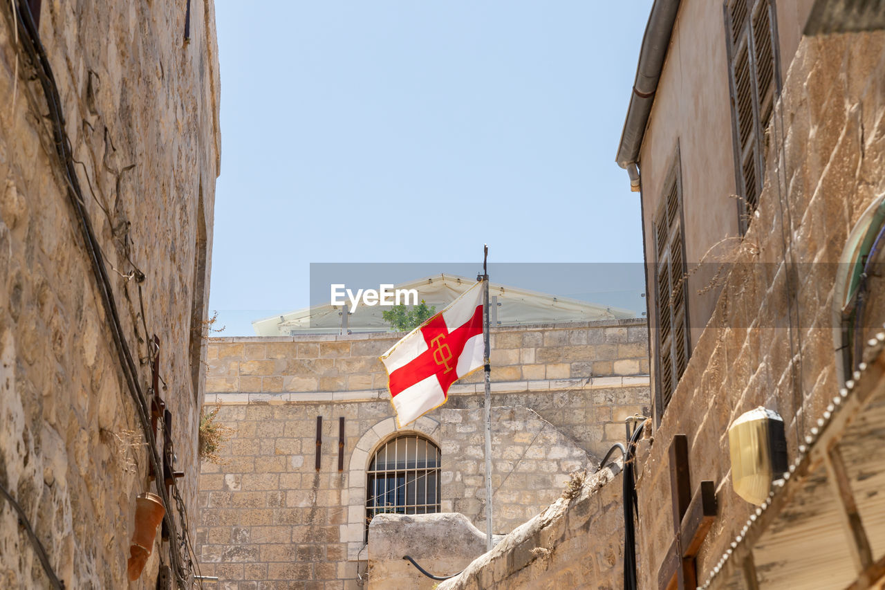 LOW ANGLE VIEW OF FLAG AMIDST BUILDINGS AGAINST SKY