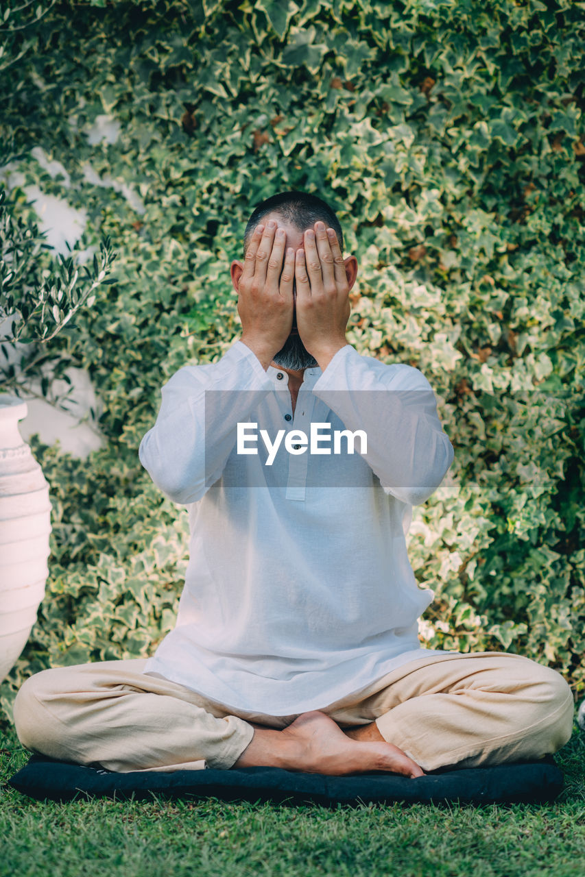 A man sitting with his eyes closed and doing reiki self-treatment