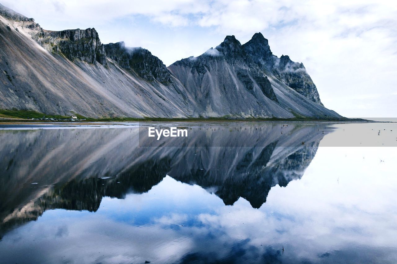 Scenic view of lake and mountains against cloudy sky