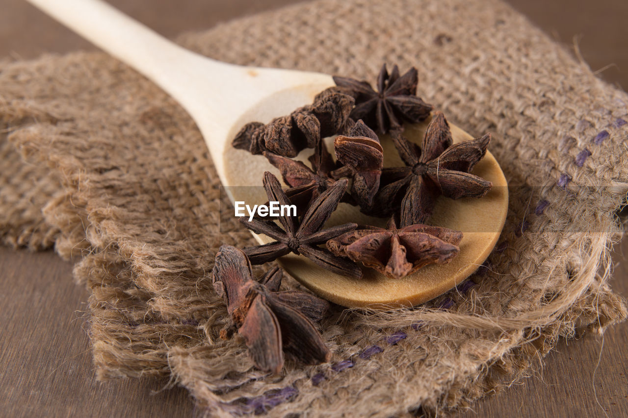 Close-up of star anise in wooden spoon with burlap on table