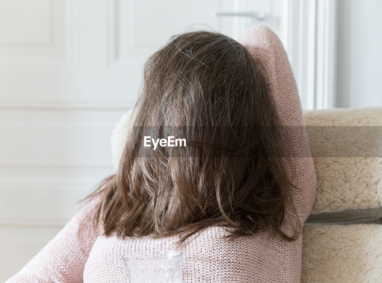 Woman with obscured face resting on sofa