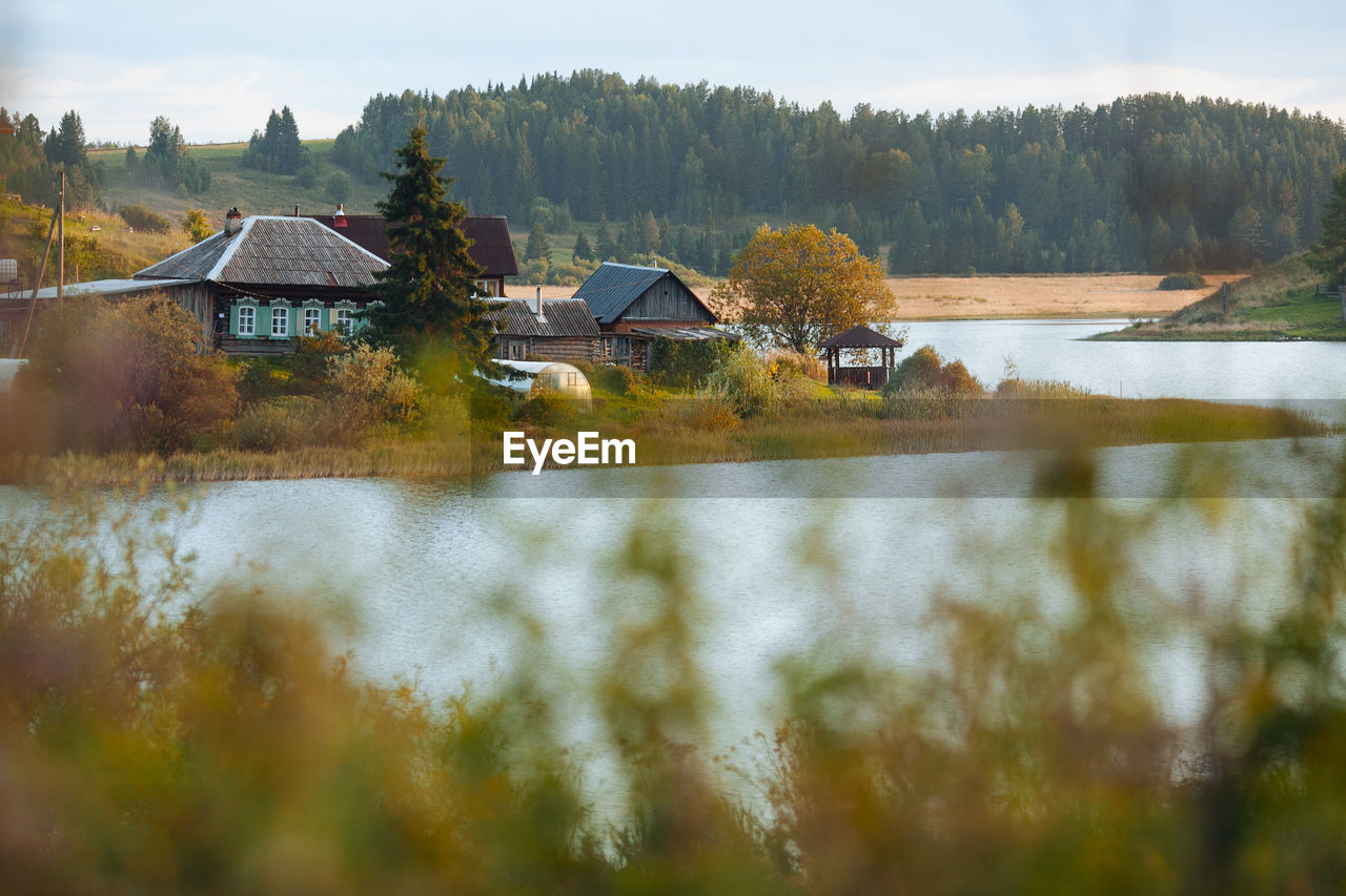 HOUSES BY LAKE AGAINST TREES AND HOUSE