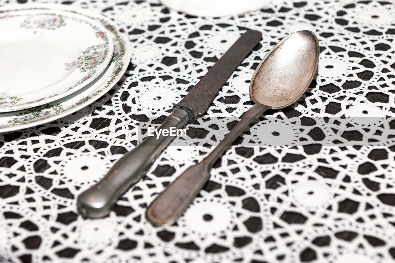 Tin spoon and knife on the table . ancient kitchen utensils . handmade embroidered tablecloth