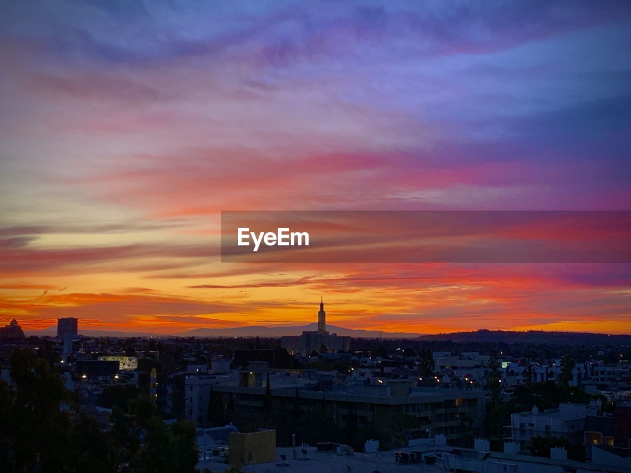 HIGH ANGLE VIEW OF CITY AGAINST CLOUDY SKY AT SUNSET