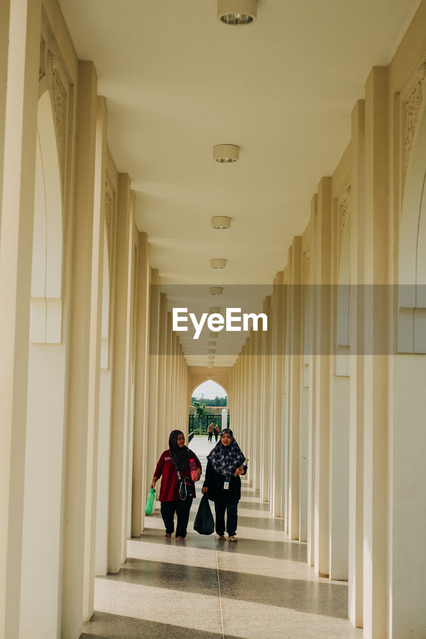 PEOPLE WALKING IN CORRIDOR OF BUILDING