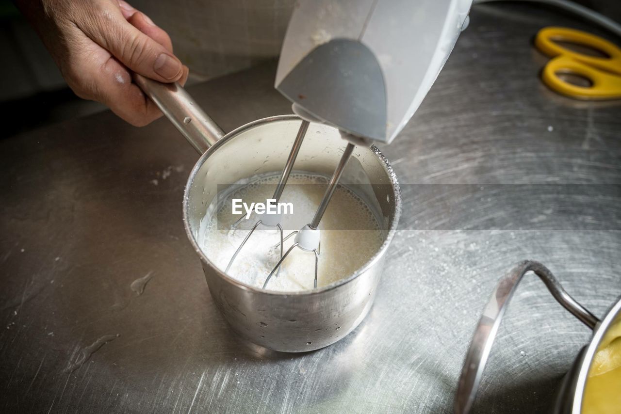 Cropped hand preparing food with wire whisk in kitchen