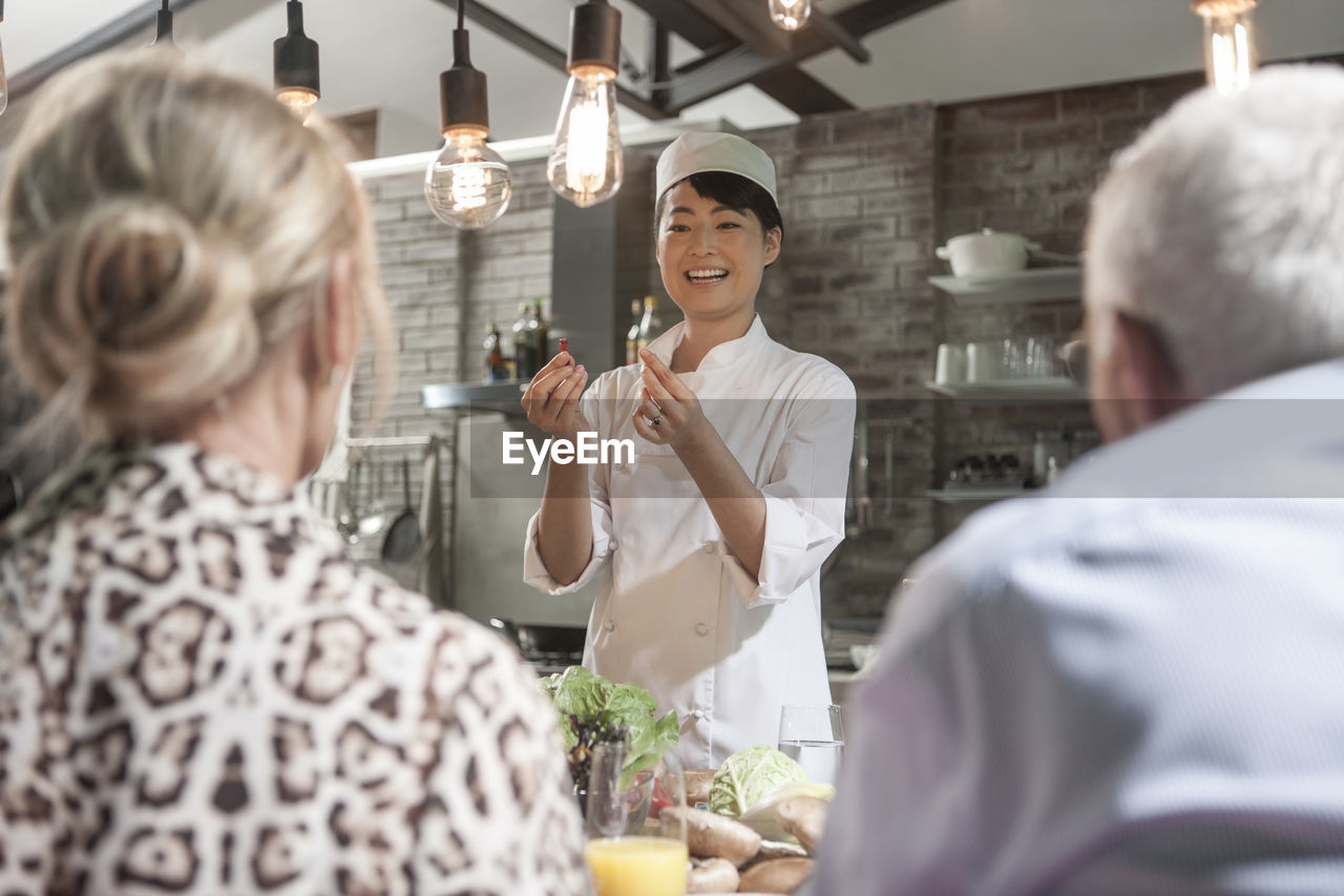 Female chef talking to senior couple in cooking class