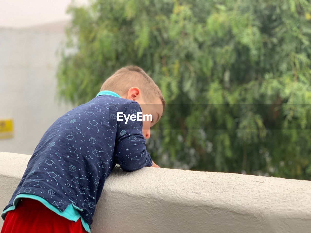 Side view of boy leaning on concrete wall