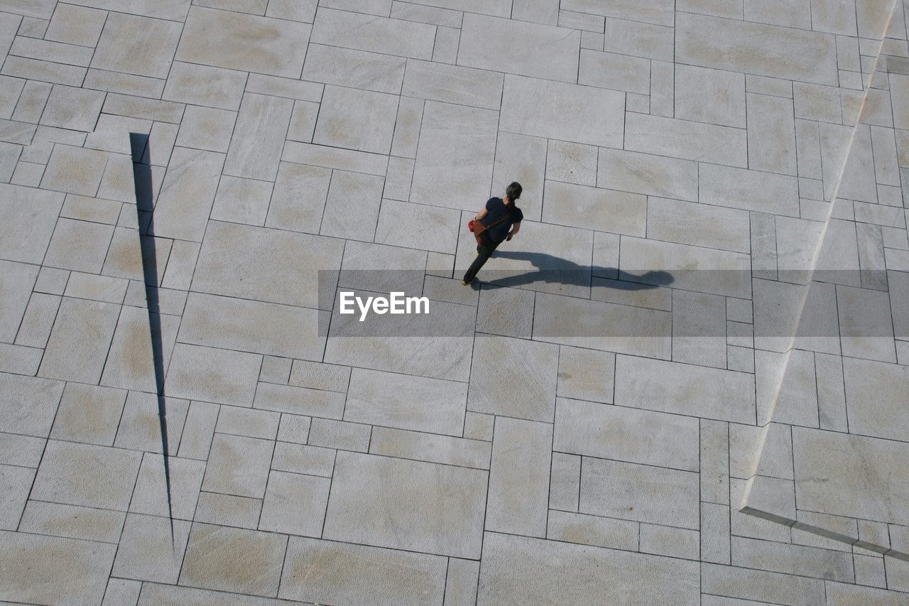 HIGH ANGLE VIEW OF MAN WALKING ON FLOORING