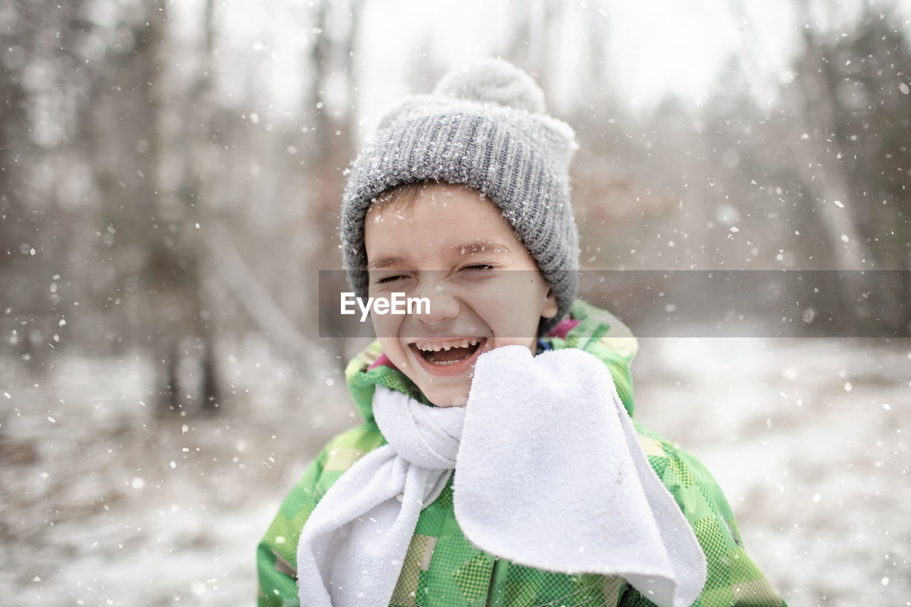 Portrait of laughing boy standing outdoors during winter