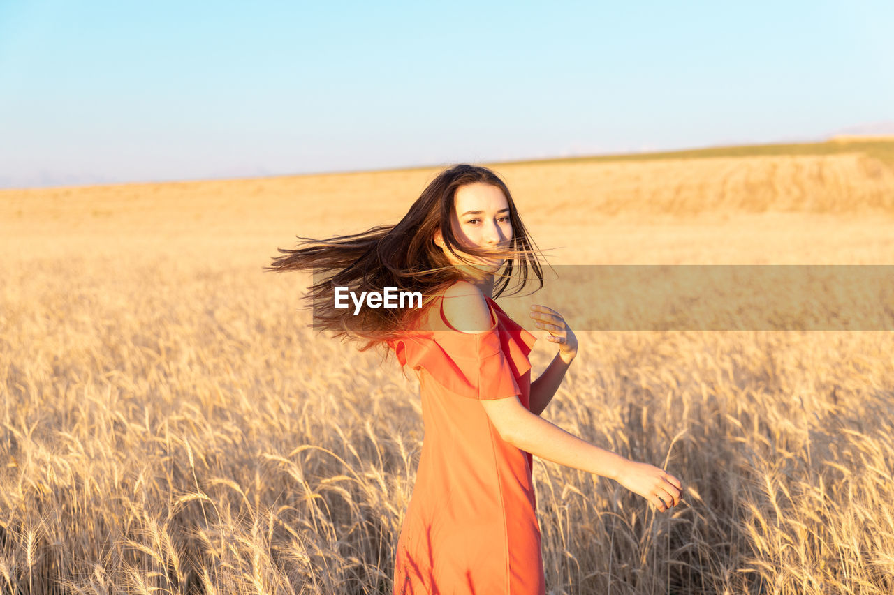 portrait of young woman standing on field