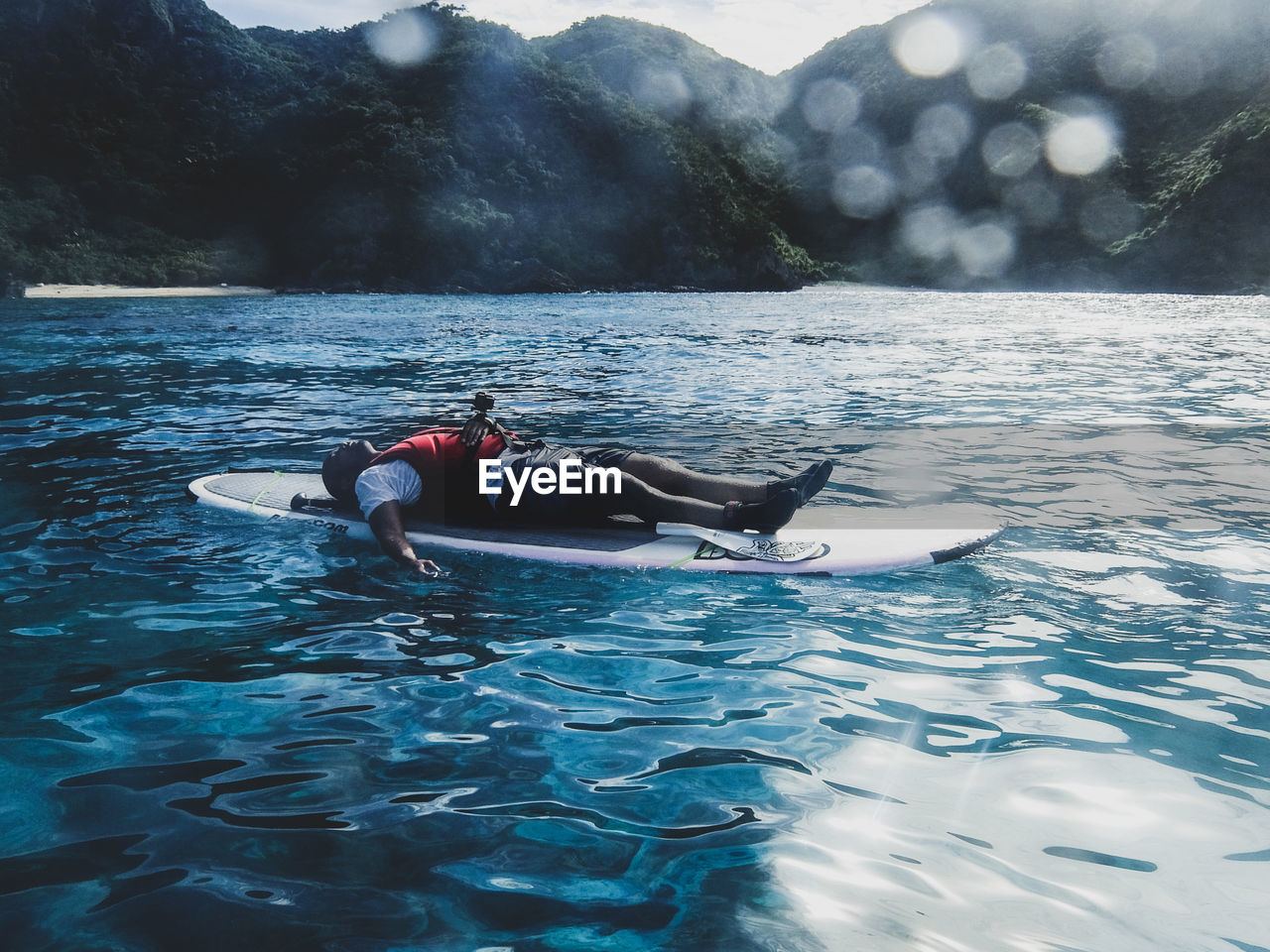 Full length of man lying on paddleboard in lake