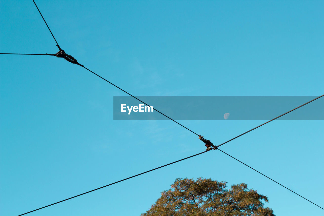 Low angle view of power lines against clear blue sky