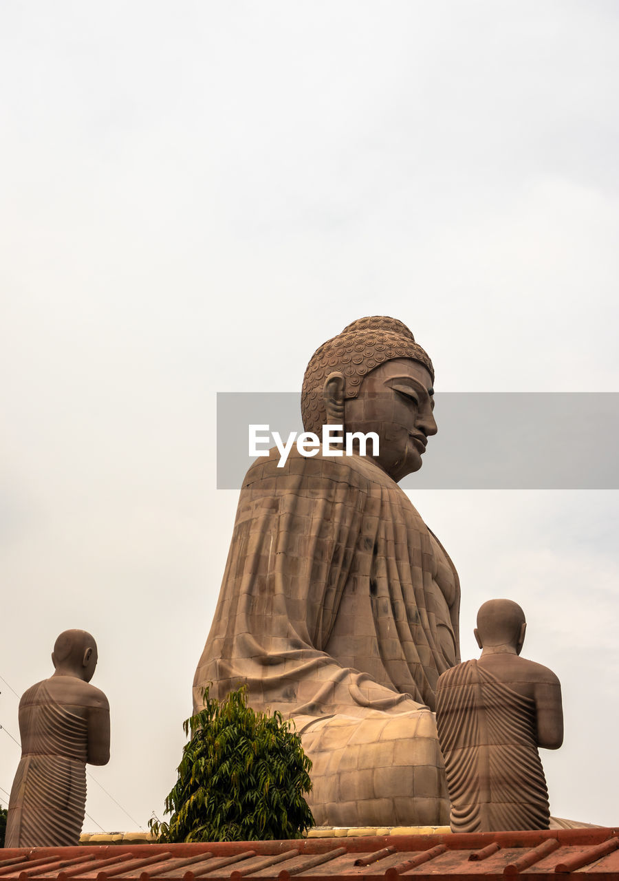 LOW ANGLE VIEW OF BUDDHA STATUE AGAINST SKY AGAINST CLEAR BLUE BACKGROUND