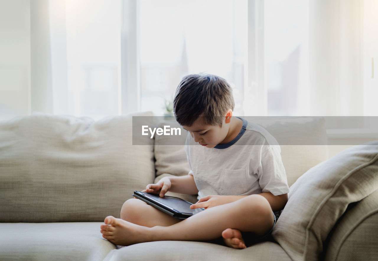 Boy looking away while sitting on sofa