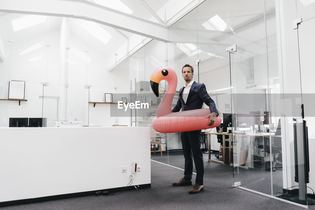 Businessman in office with inflatable flamingo