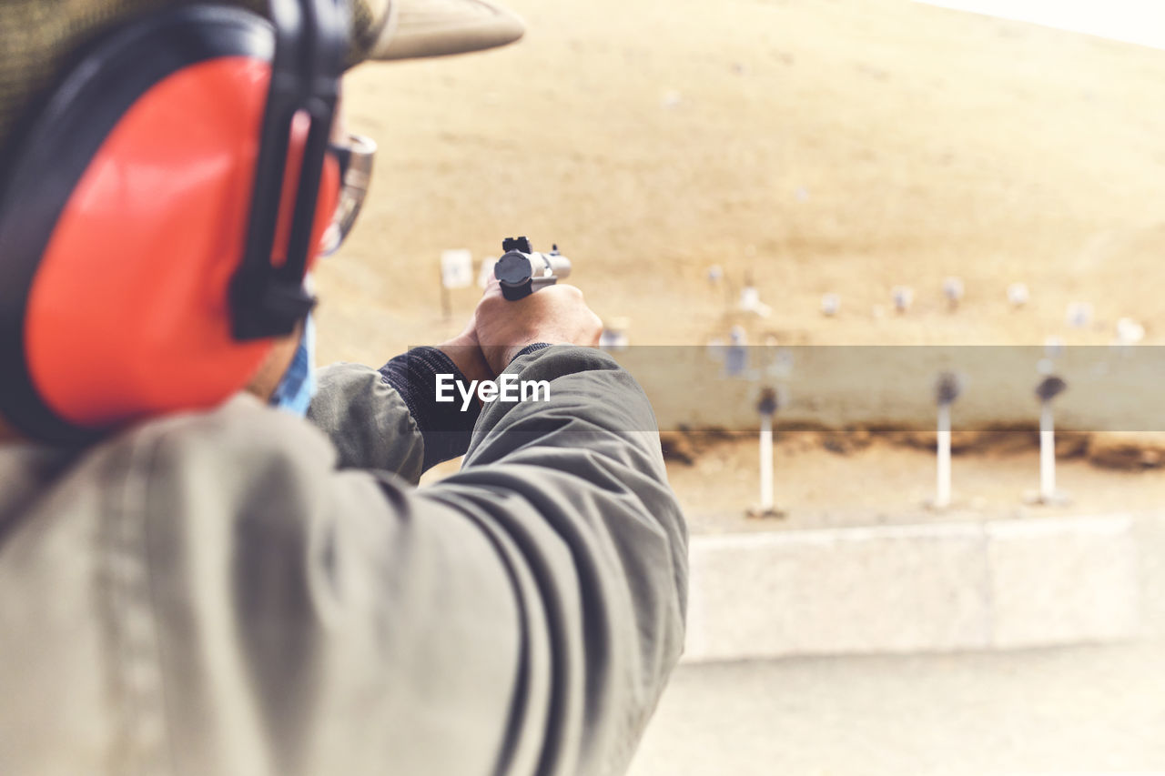 Man with hand gun aiming at shooting range and releasing stress. selective focus