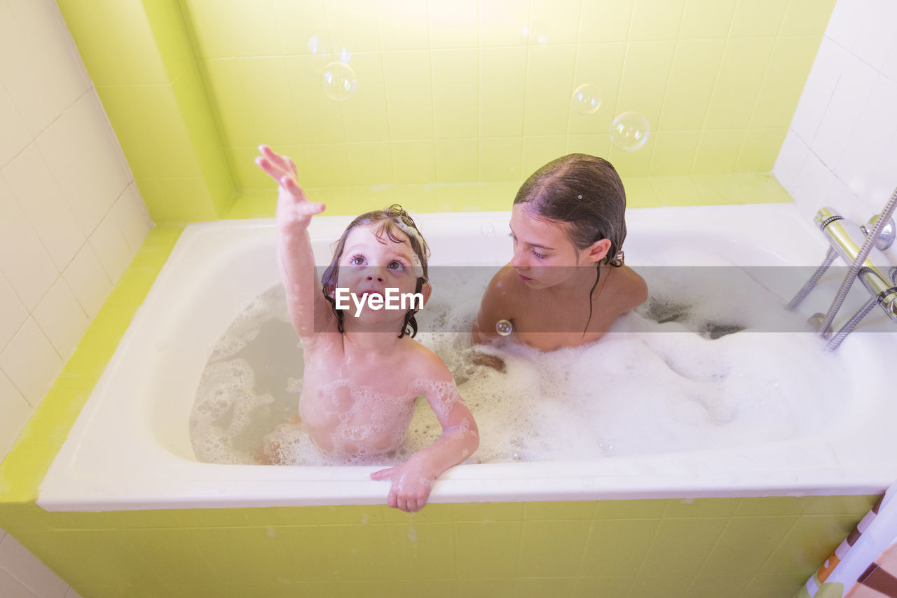 High angle view of siblings playing in bathtub