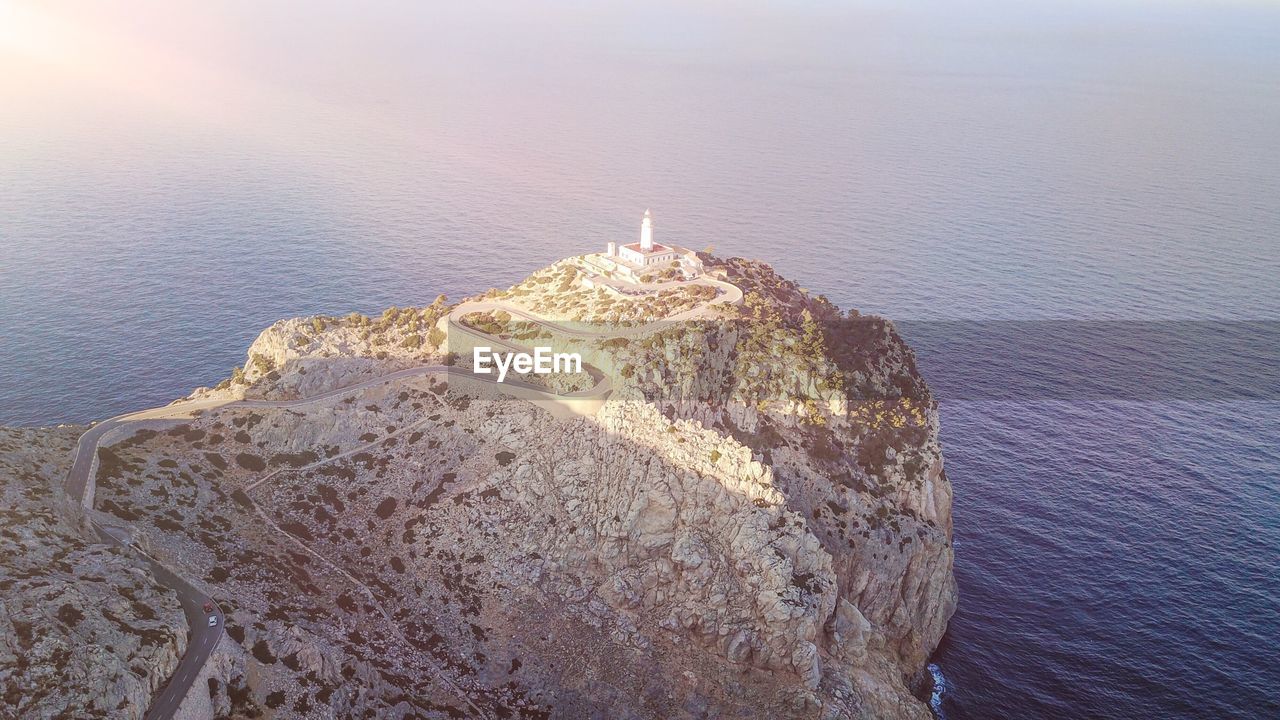 Aerial view of lighthouse on cliff against sea