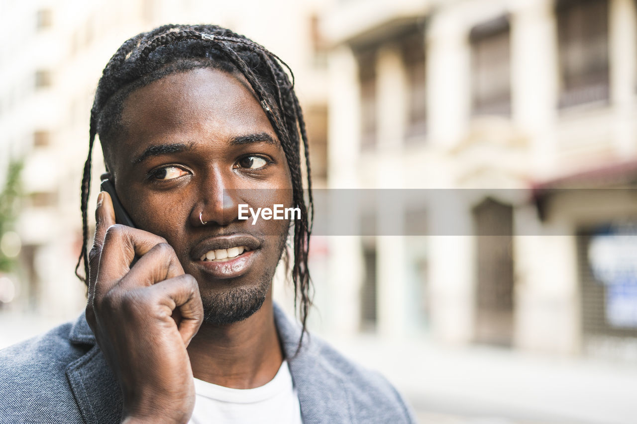 Close-up of young man talking on mobile phone in city