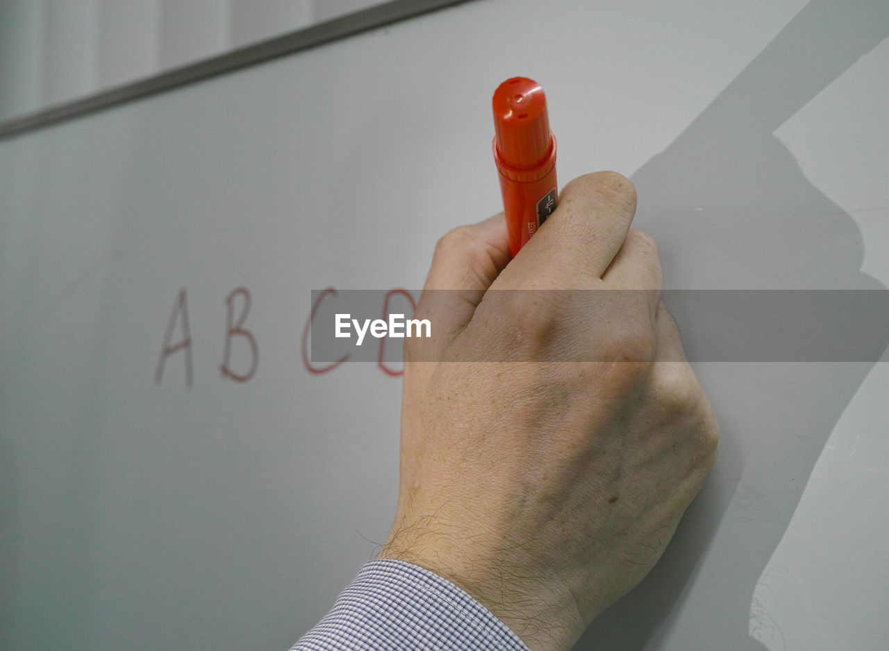 Close-up of hand writing on whiteboard