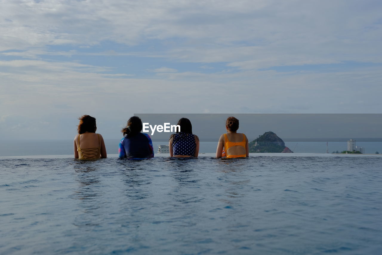 Rear view of friends relaxing in infinity pool